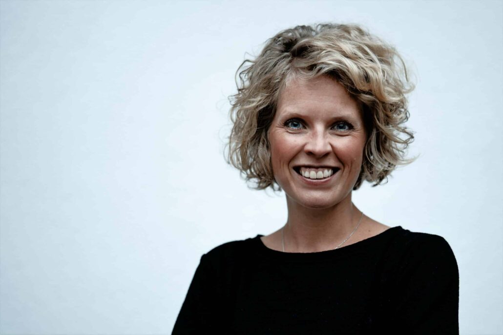 Portrait einer freundlichen Frau mit lockigem Haar, die für die Werte von Unsere Grüne Glasfaser steht.