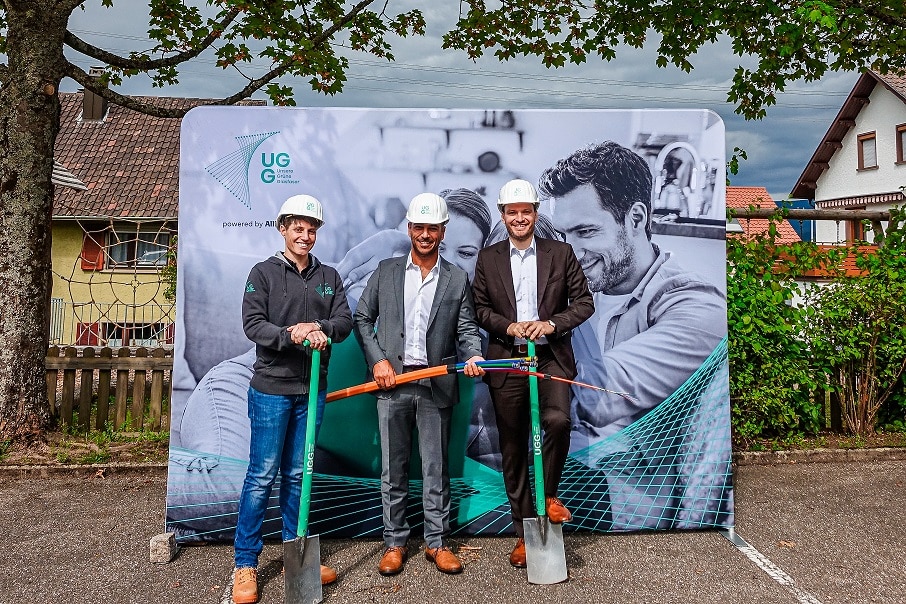 Drei Männer mit Schaufeln und Helm präsentieren den Start eines Glasfaserprojekts von Unsere Grüne Glasfaser.