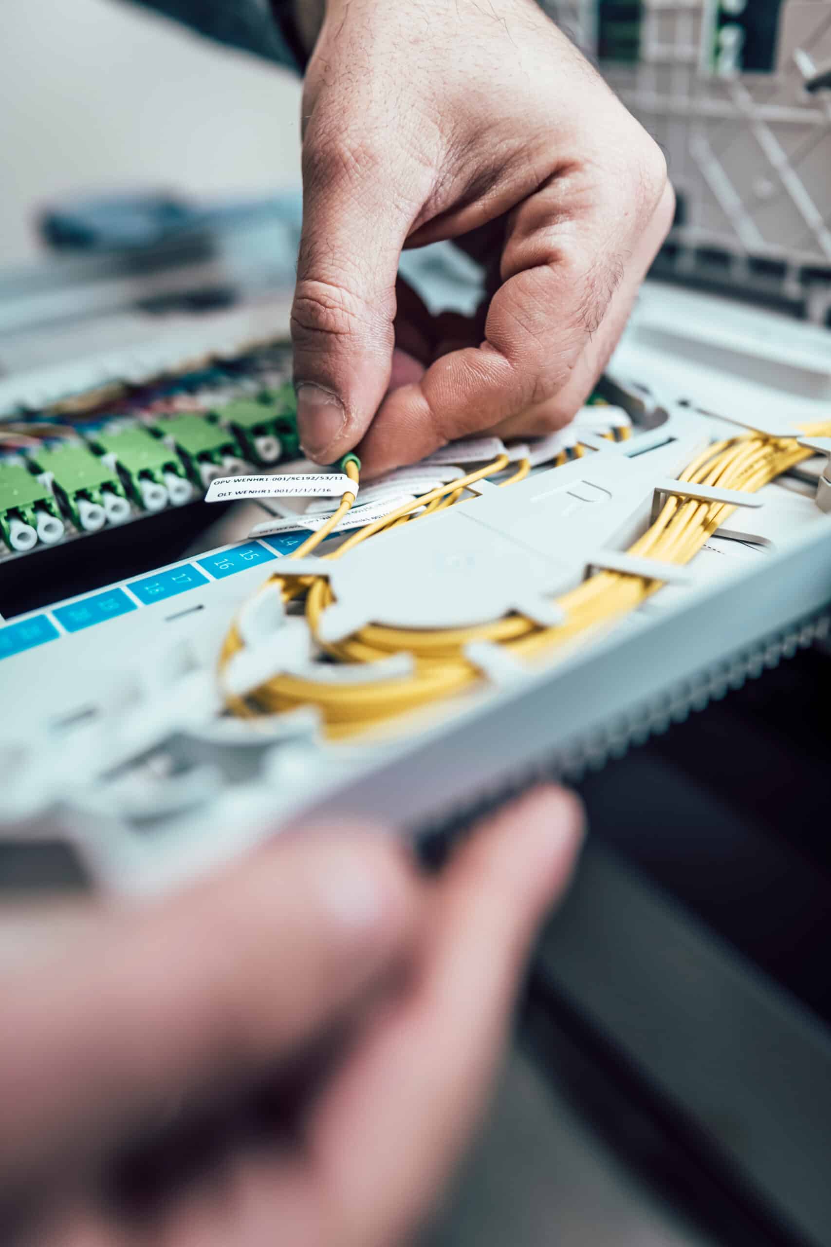 Techniker installiert Glasfaserkabel in einem Verteiler, um schnelle Internetverbindungen für unsere Kunden zu gewährleisten.