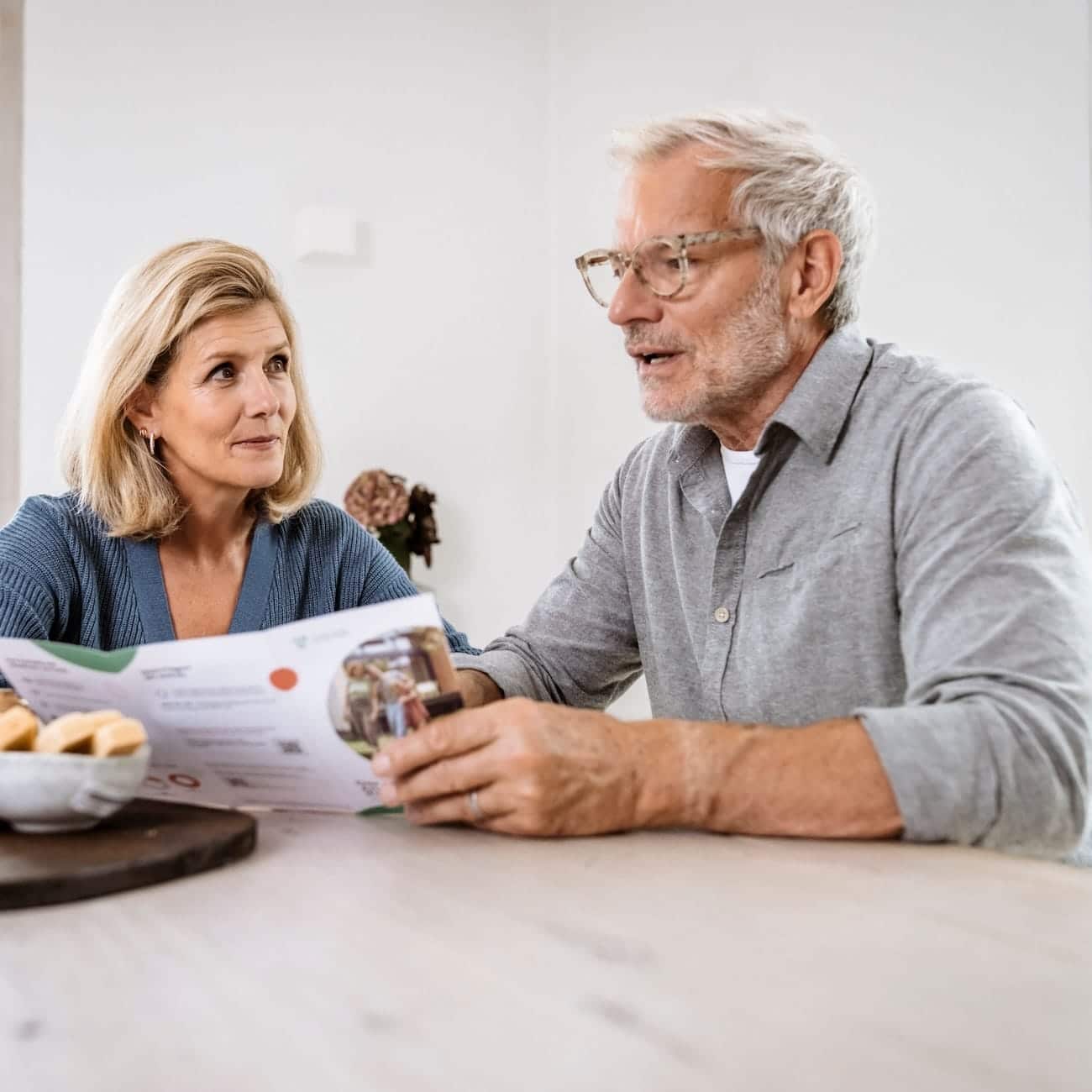 Älteres Paar bespricht Informationen zu Glasfaseranschlüssen am Tisch, um die Vorteile von schnellerem Internet zu erkunden.
