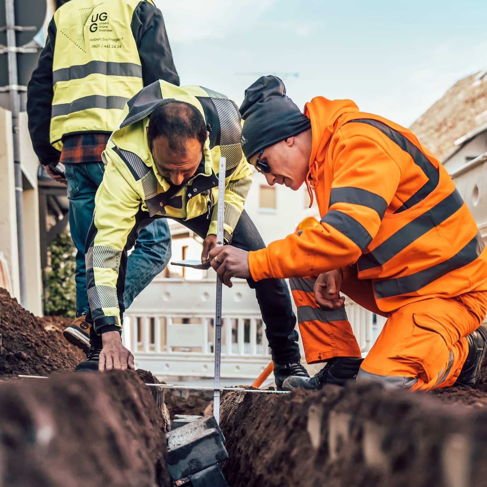 Arbeiter verlegen Glasfaserleitungen in einem Graben, um die Internetinfrastruktur von Unsere Grüne Glasfaser zu verbessern.