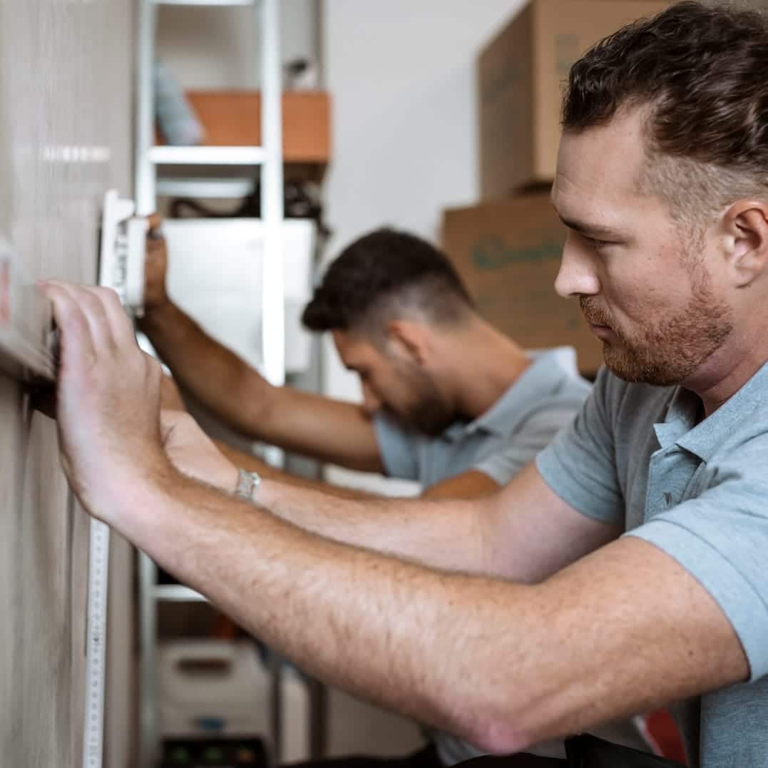 Techniker von Unsere Grüne Glasfaser messen präzise für die Installation von Hochgeschwindigkeitsinternet in einem Wohnraum.
