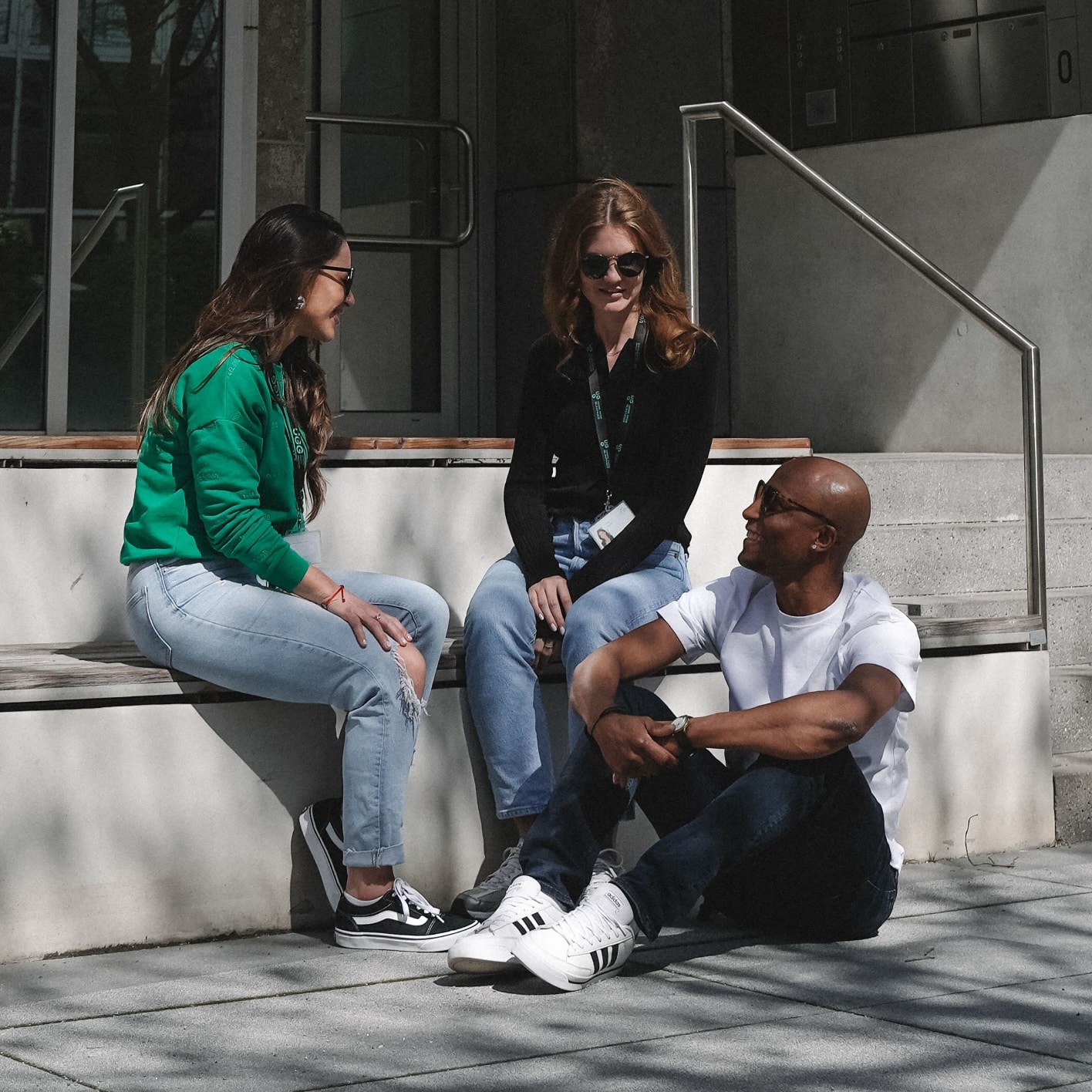 Junge Erwachsene diskutieren entspannt auf einer Treppe, symbolisieren Gemeinschaft und Innovation bei Unsere Grüne Glasfaser.