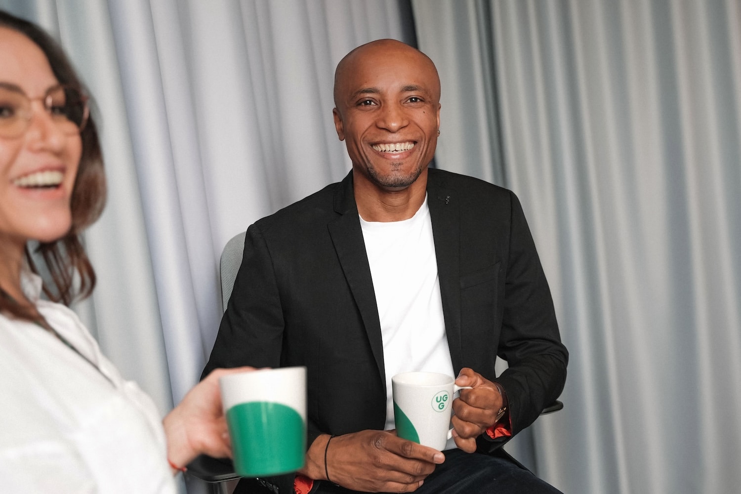 Lächelnde Personen mit Tassen in den Händen, symbolisieren die freundliche Atmosphäre von Unsere Grüne Glasfaser.