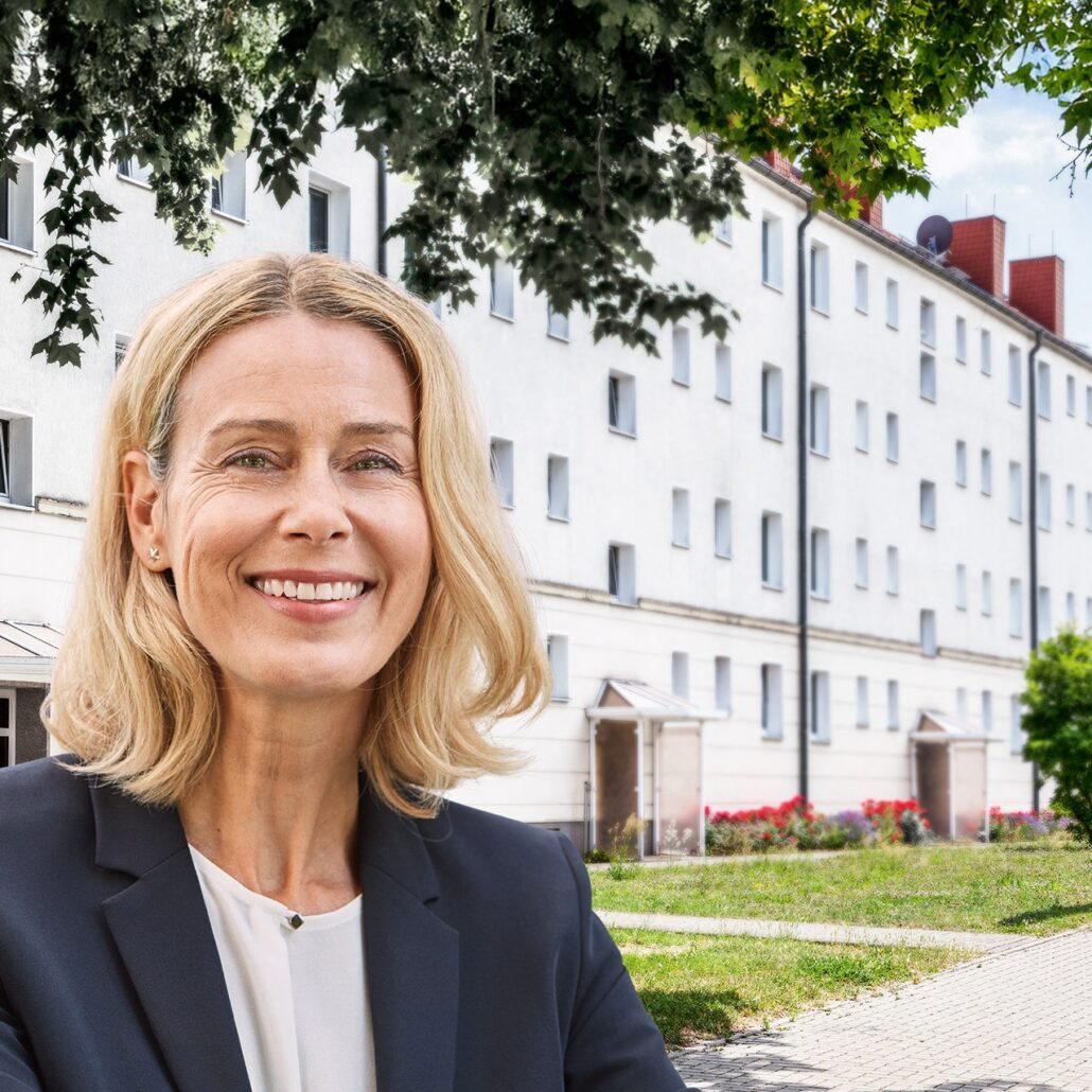 Frau lächelt vor einem modernen Wohngebäude, symbolisiert die Zukunft des schnellen Internets mit Unsere Grüne Glasfaser.