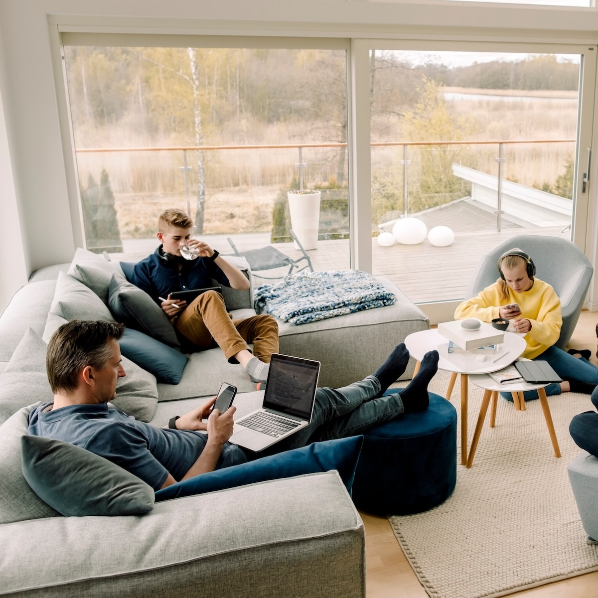 Familie nutzt modernes Homeoffice mit Glasfaser-Internet für Arbeit und Freizeit in einem hellen Wohnzimmer.