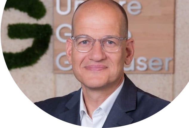 Porträt eines Mitarbeiters von Unsere Grüne Glasfaser vor dem Unternehmenslogo, das für nachhaltige Internetlösungen steht.