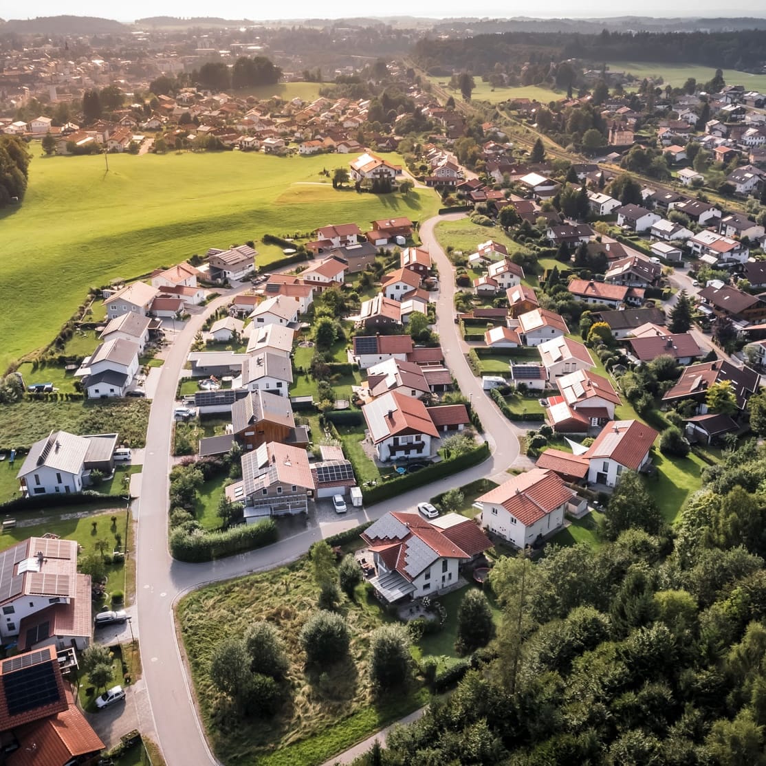 Luftaufnahme eines Wohngebiets mit Einfamilienhäusern und umgebender Natur, ideal für schnelle Glasfaseranschlüsse.