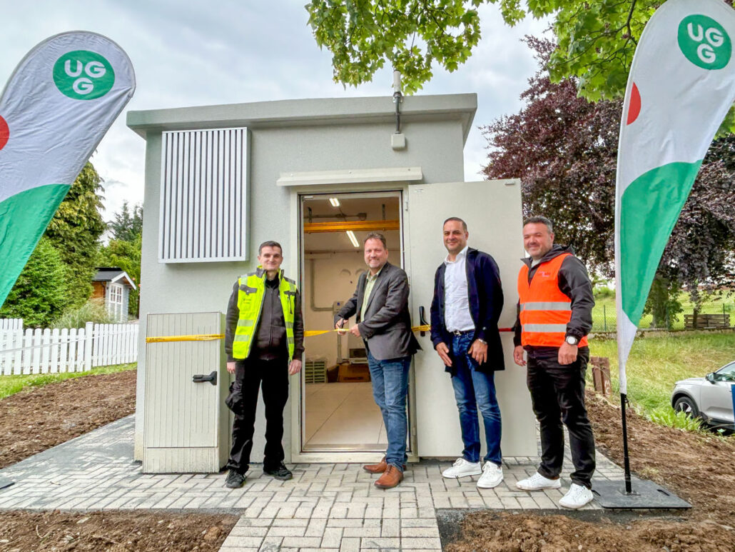 Eröffnung eines neuen Standorts von Unsere Grüne Glasfaser mit Vertretern und Flaggen am Gebäude.