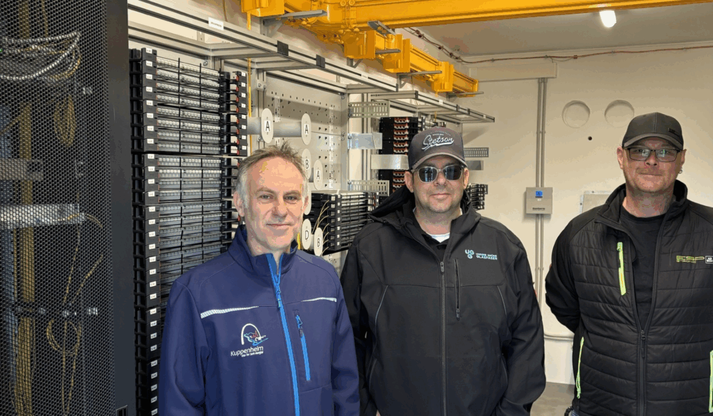 Techniker von Unsere Grüne Glasfaser in einem Netzwerkraum, umgeben von moderner Ausrüstung und Glasfaserverbindungen.