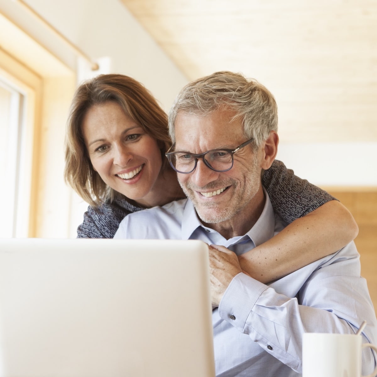 Glückliches Paar sitzt am Laptop und genießt die Vorzüge von schnellem Internet mit Unsere Grüne Glasfaser.