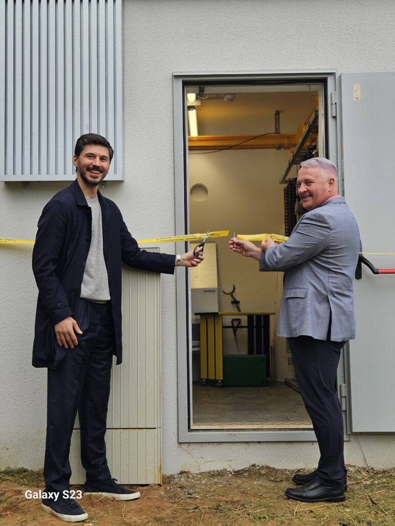 Zwei Mitarbeiter von Unsere Grüne Glasfaser eröffnen eine neue Anlage zur Verbesserung der Internetversorgung.