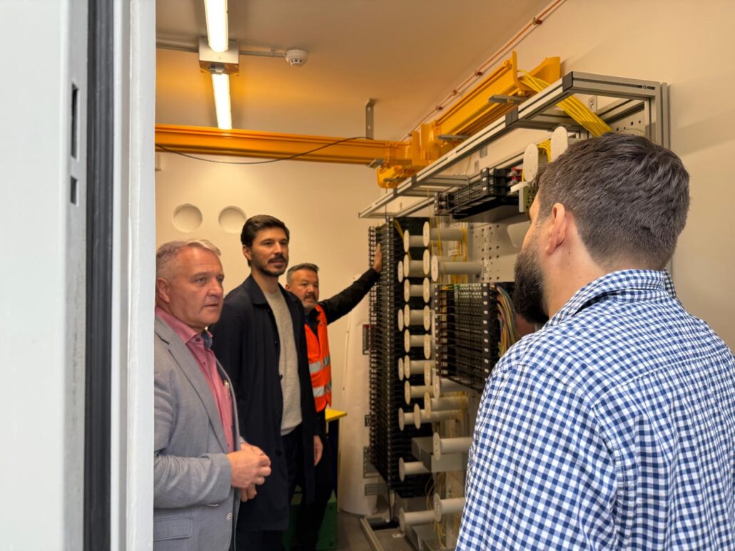 Techniker besprechen den Aufbau einer Glasfaseranlage bei "Unsere Grüne Glasfaser" in einem modernen Technikraum.